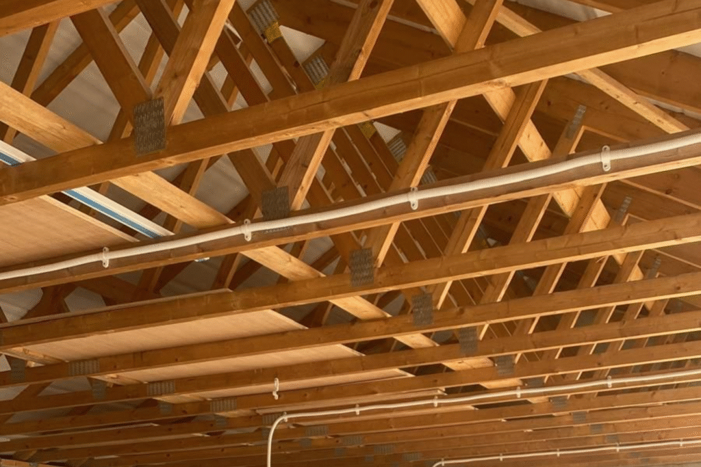 Wooden truss ceiling structure with exposed beams and insulation panels, illustrating structural engineering principles relevant to construction projects by Solved Construction in Wakefield.