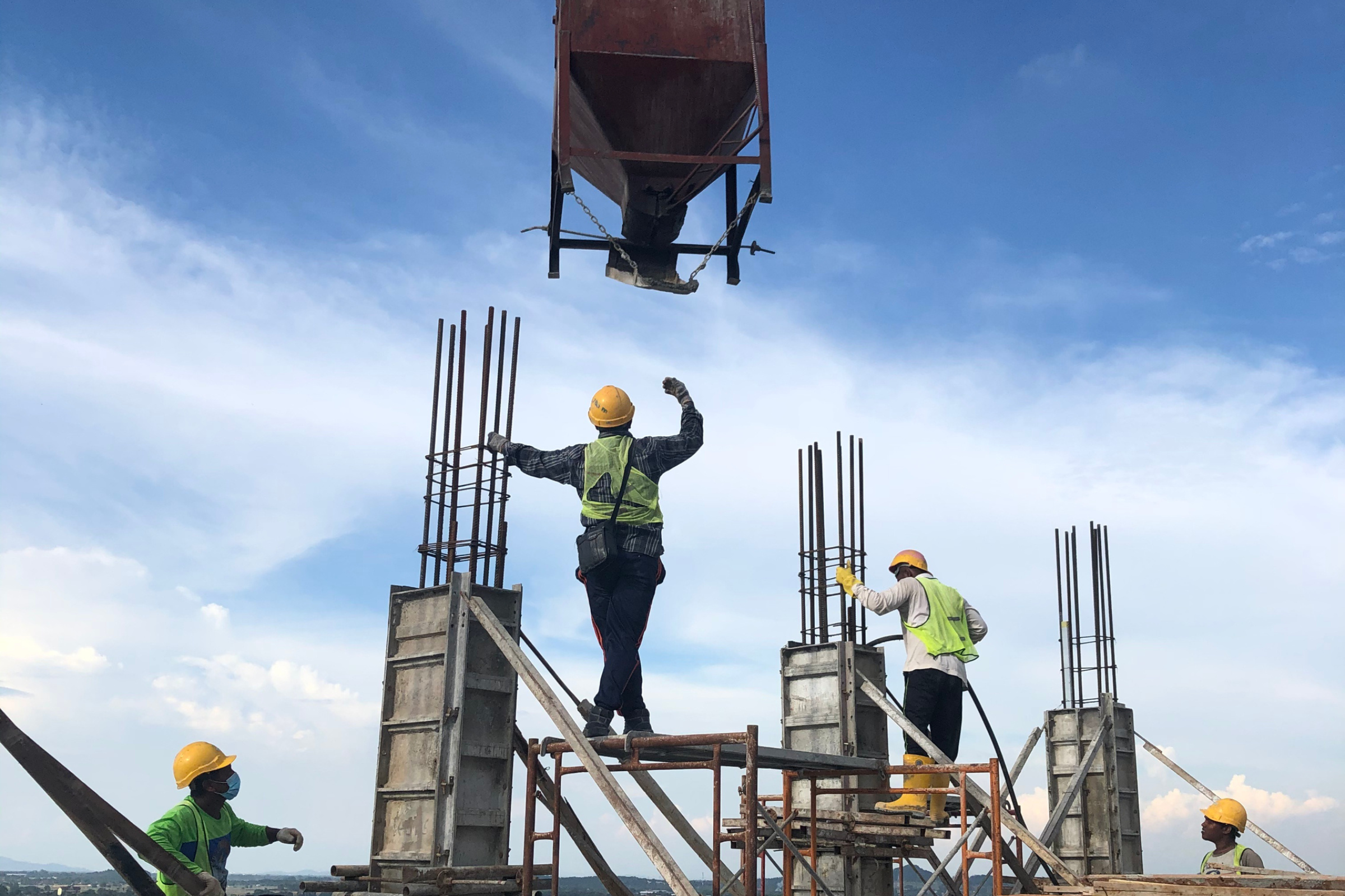 Construction workers in safety gear operating a concrete mixer and preparing structures with rebar, emphasizing skilled labor and construction services in Ossett.
