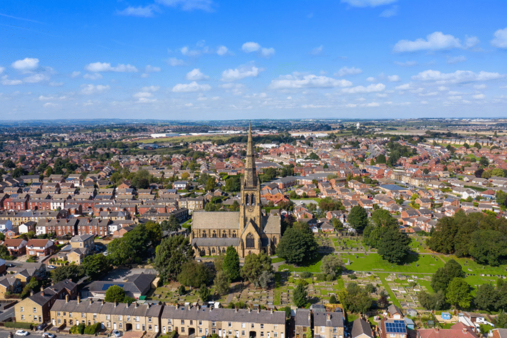 Aerial view of a church surrounded by residential homes and green spaces in a town, representing the community served by Solved Construction in various construction and renovation projects.