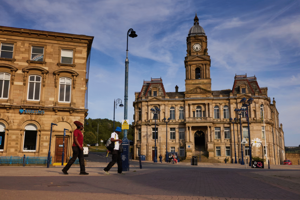 Historic building in Castleford with clock tower, pedestrians walking by, and modern streetscape elements.