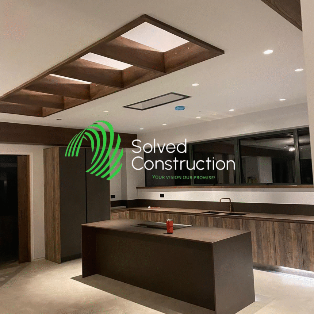 Modern kitchen interior featuring wooden cabinetry, sleek countertops, and ambient lighting, with Solved Construction logo and tagline prominently displayed.
