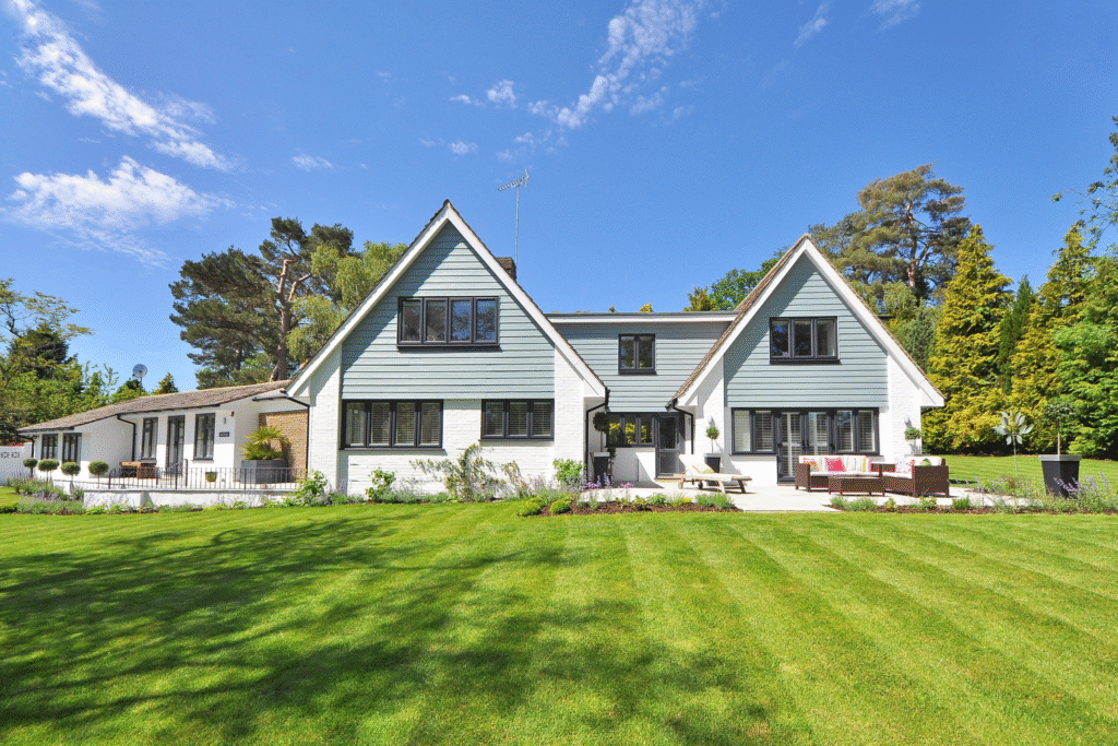 Modern residential home with landscaped lawn, featuring a mix of traditional and contemporary architecture, surrounded by trees, emphasizing renovation and construction expertise.